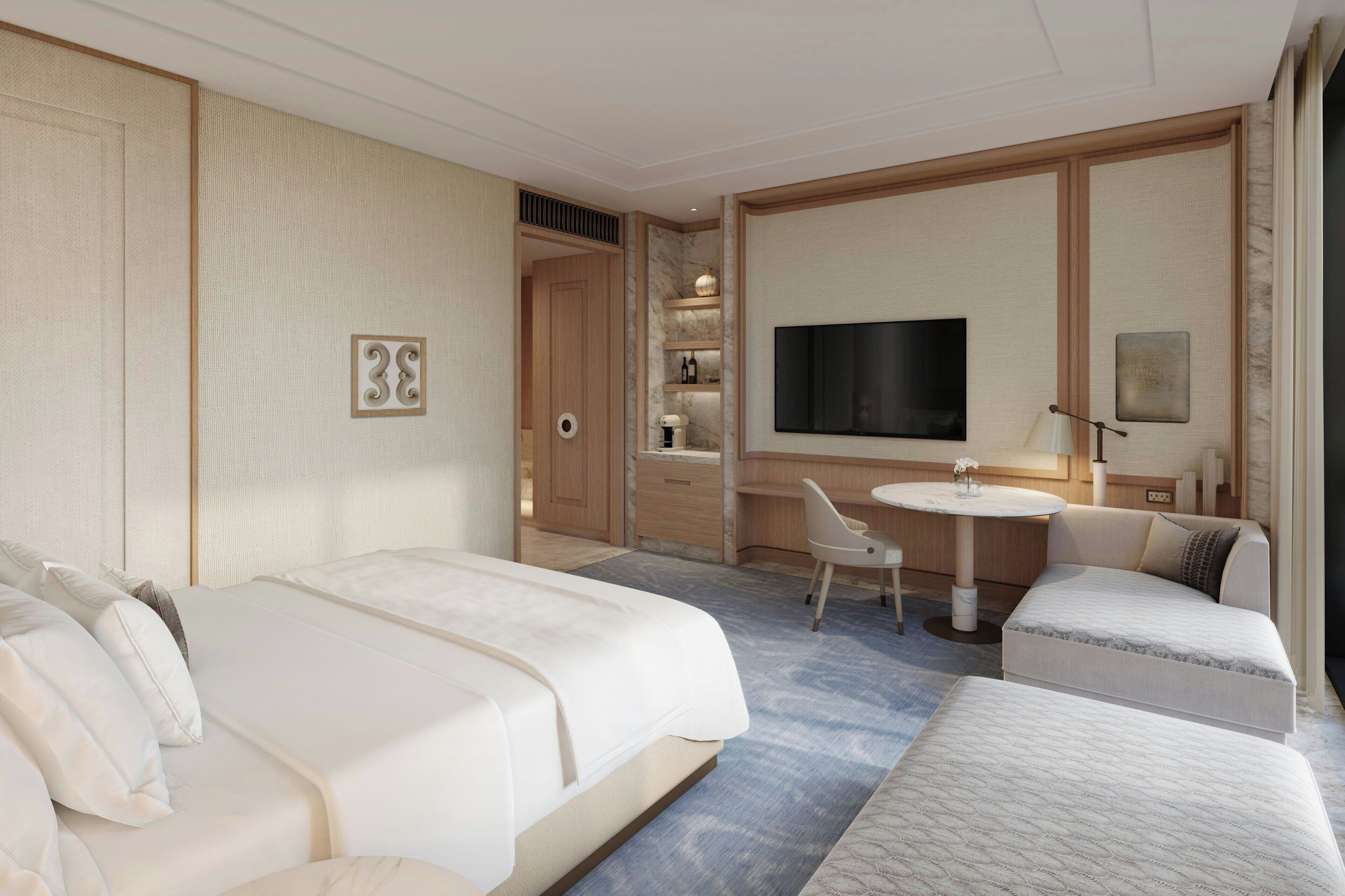 Quarto de hotel com uma cama grande, uma cama menor, uma escrivaninha com cadeira, uma televisão e uma mesinha.
