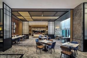 A modern restaurant with a central bar area, multiple dining tables, and chairs. - Four Points By Sheraton Linyi Hedong (Linyi)