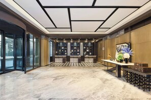 A hotel lobby with a checkered floor, a reception desk, and a wall of display cabinets. - Four Points By Sheraton Linyi Hedong (Linyi)