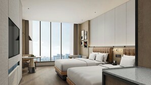 Una habitación de hotel moderna con dos camas, una zona de comedor, un televisor y vistas a la ciudad.