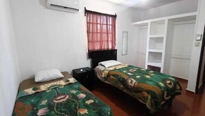 Een kamer met twee bedden, een kledingkast, een plafondventilator en een airconditioning.