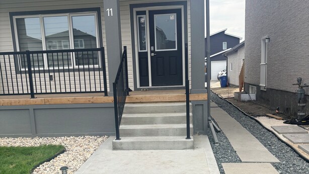 A residential house with a front porch, a staircase leading to the entrance, and a driveway. - Victorious Place(STRA-2025-2882840) (Winnipeg)