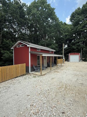 Un bâtiment rouge avec un porche couvert et un garage.