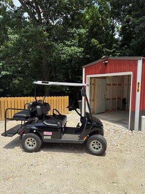 Une voiturette de golf est garée devant un bâtiment doté d’un toit rouge et d’une porte blanche.