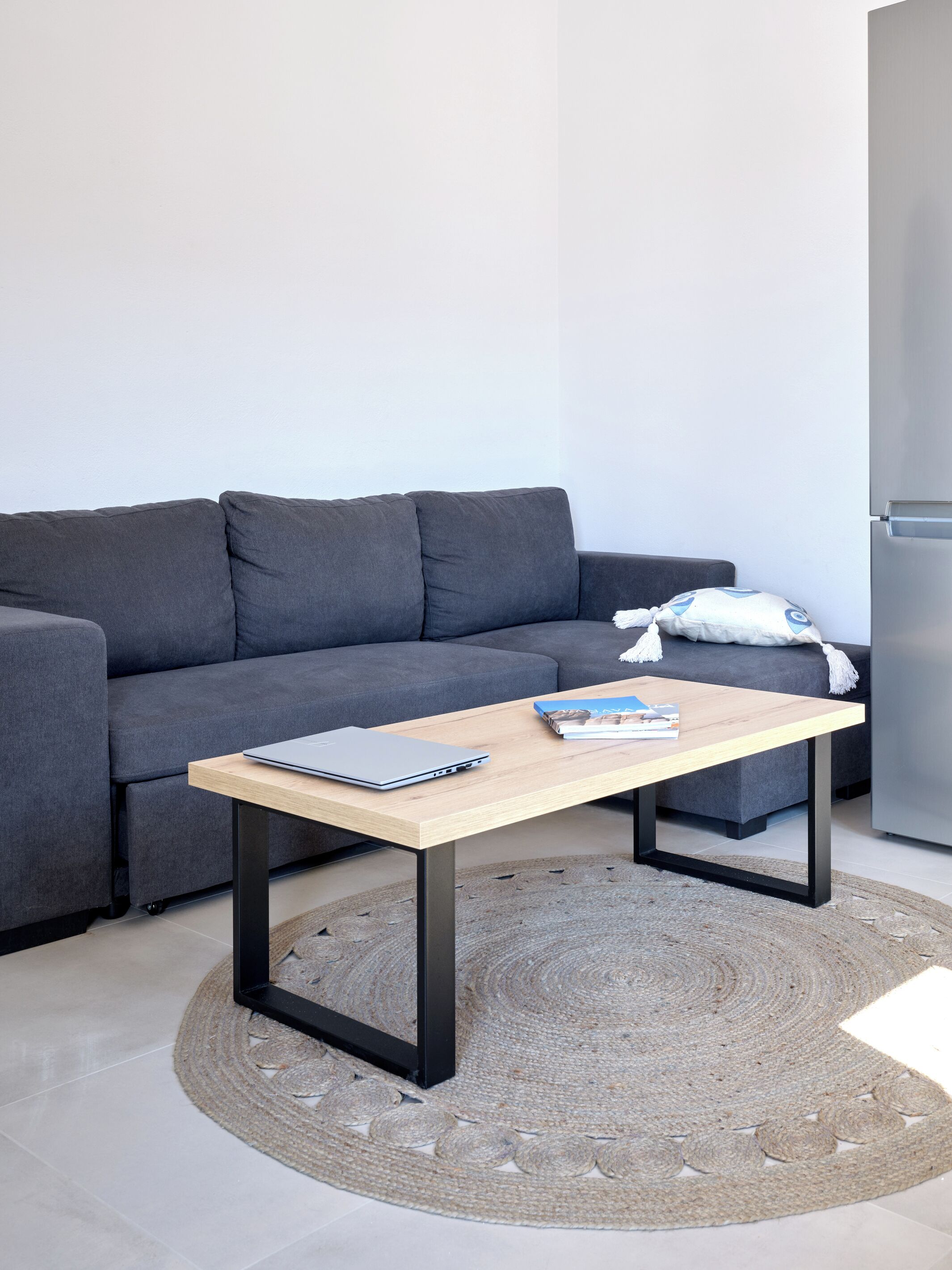 A modern living room with a grey sofa, a wooden coffee table, and a small rug.