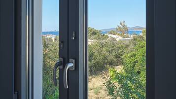 Una ventana con vistas a un paisaje costero, que incluye vegetación y una masa de agua distante.