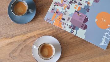Zwei Kaffeetassen auf einem Holztisch mit einem farbenfrohen, abstrakten Muster und einem Buch.