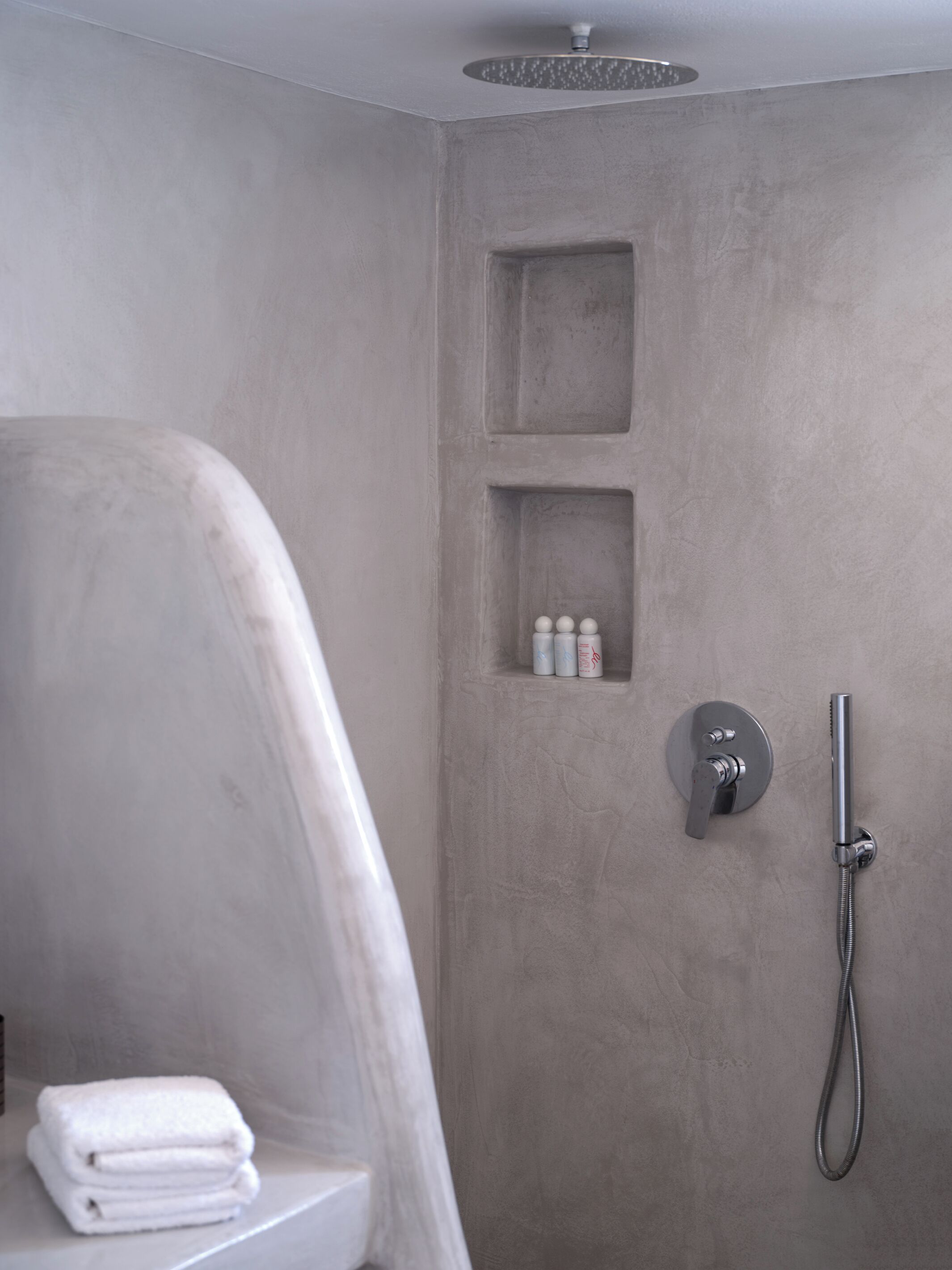 Ein Badezimmer mit Dusche, Toilette und gestapelten Handtüchern.