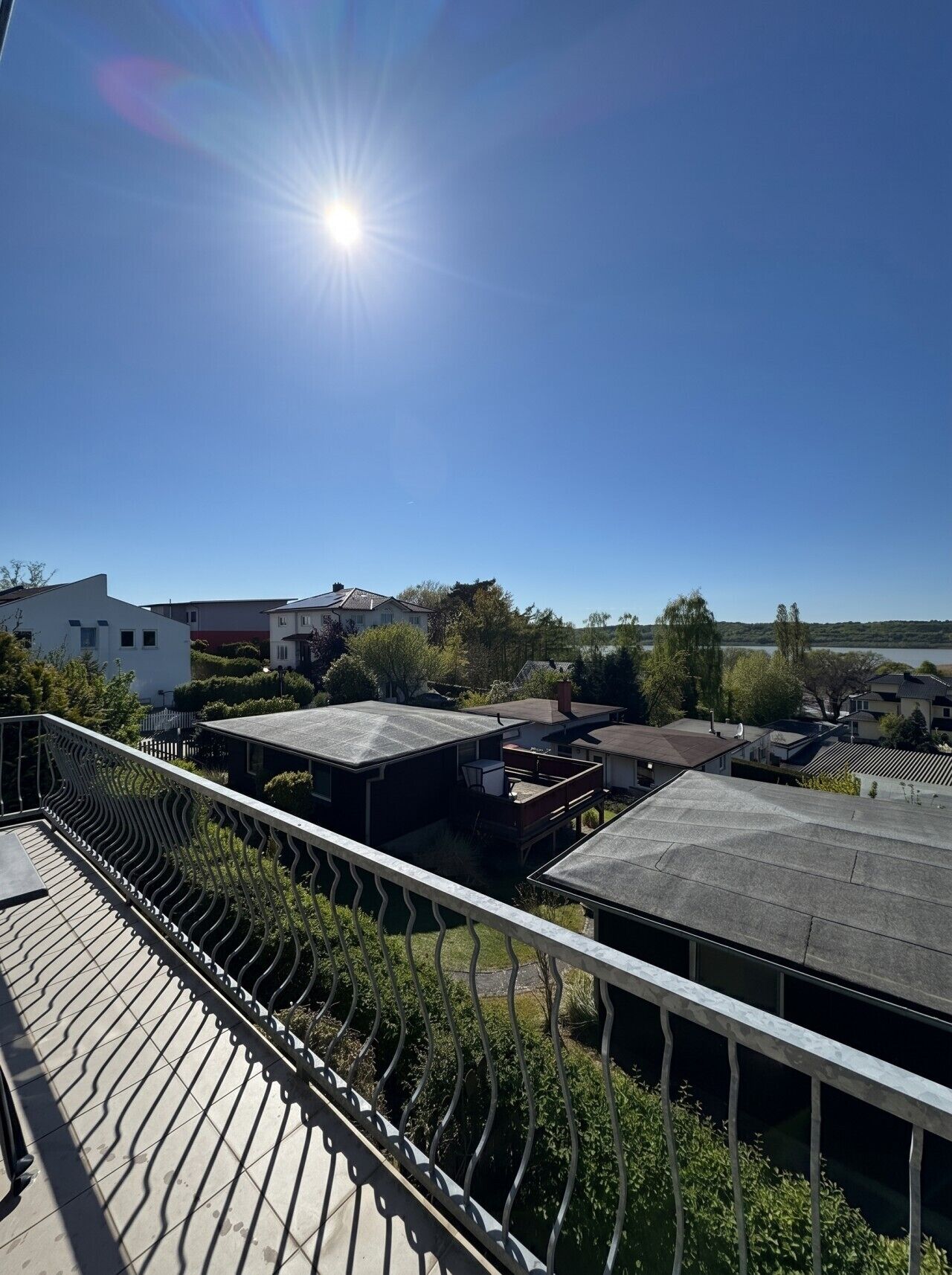 Un quartier résidentiel avec des maisons, un ciel dégagé et un soleil brillant.