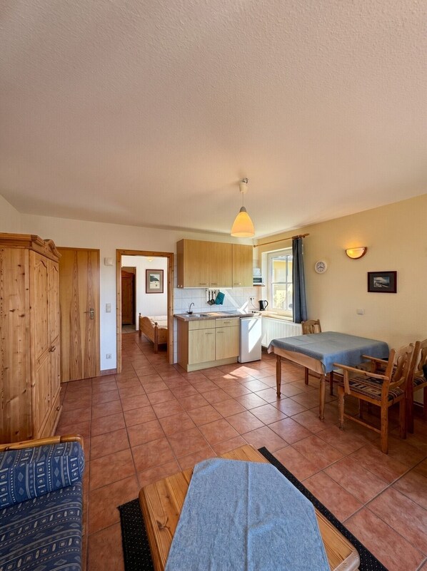 A cozy room with a bed, a small table, a sofa, and a kitchenette. - Haus Seeblick - Comfort Apartment No. 2 with lake view (Binz)