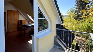 Un immobile residenziale con patio coperto, una porta scorrevole in vetro che dà su un ambiente interno e vista su vegetazione circostante.