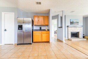 Una cocina con un refrigerador de acero inoxidable, armarios de madera y una chimenea.