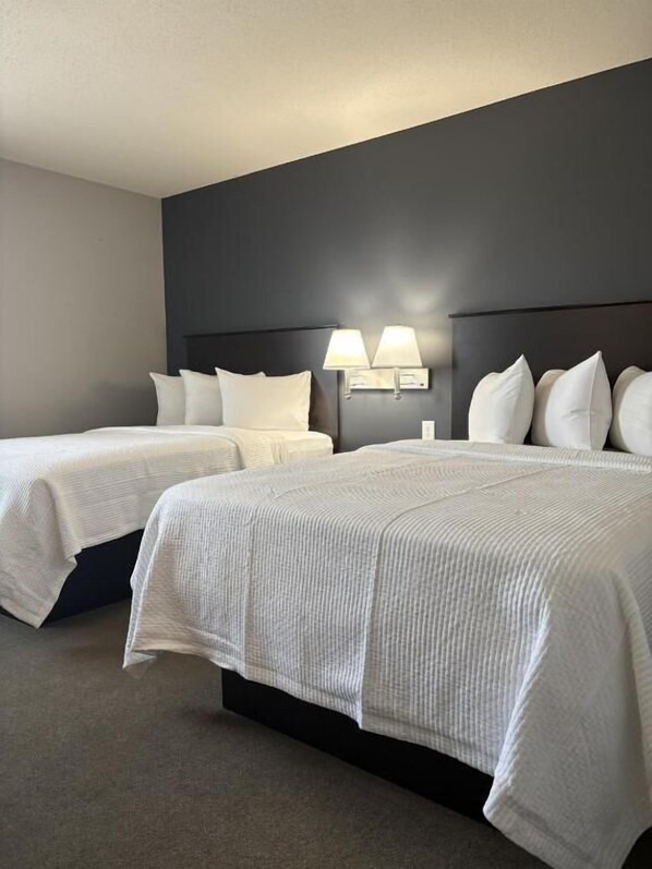 Ein Hotelzimmer mit zwei Betten, einem dunklen Kopfteil und Wandleuchten.