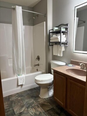 A bathroom with a shower, toilet, sink, and a mirror. - Prairie Inn of Jamestown (Jamestown)
