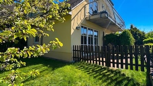 A two-story house with a balcony, a picket fence, and a well-maintained lawn. - House Seeblick - Garden Suite No. 4 (Binz)