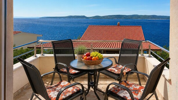 Ein Balkon mit Tisch, Stühlen und einer Obstschale.