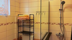 Ein Badezimmer mit Duschkabine aus Glas, einem Handtuchhalter mit gefalteten Handtüchern und einer Toilette.