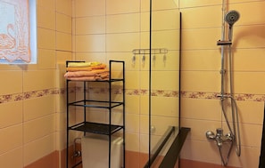 Ein Badezimmer mit Duschkabine aus Glas, einem Handtuchhalter mit gefalteten Handtüchern und einer Toilette.