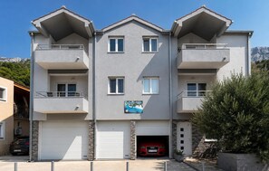 Ein mehrstöckiges Gebäude mit Balkonen, einer Garage und einem Schild, das es als Wohnkomplex kennzeichnet.