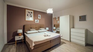 Ein Schlafzimmer mit Bett, Nachttischen, einem Kleiderschrank und Wandbildern.