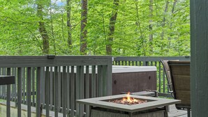 A deck with a fire pit, a chair, and a view of a forest. - Peaceful 4-bedroom cabin with AC in charming Cosby (Cosby)