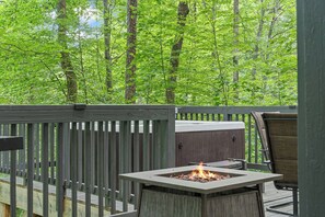 A deck with a fire pit, a chair, and a view of a forest. - Peaceful 4-bedroom cabin with AC in charming Cosby (Cosby)