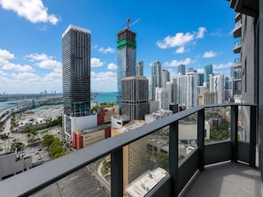 Un immeuble de grande hauteur offrant une vue sur le paysage urbain, notamment sur un chantier de construction et une marina.