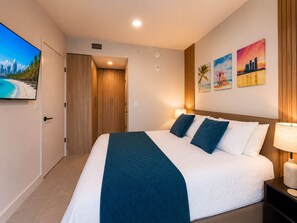 Ein Hotelzimmer mit Bett, Fernseher, Tür und Bildern an der Wand.