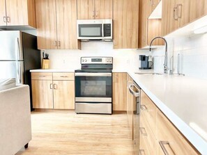 Eine moderne Küche mit Holzschränken, Edelstahlgeräten und einer weißen Arbeitsplatte.