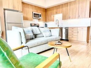 Eine moderne Küche mit Holzausstattung, einem Edelstahlkühlschrank, einer Mikrowelle und einem Spülbecken.