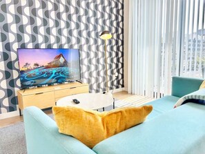 Ein modernes Wohnzimmer mit Fernseher, Sofa und Lampe.
