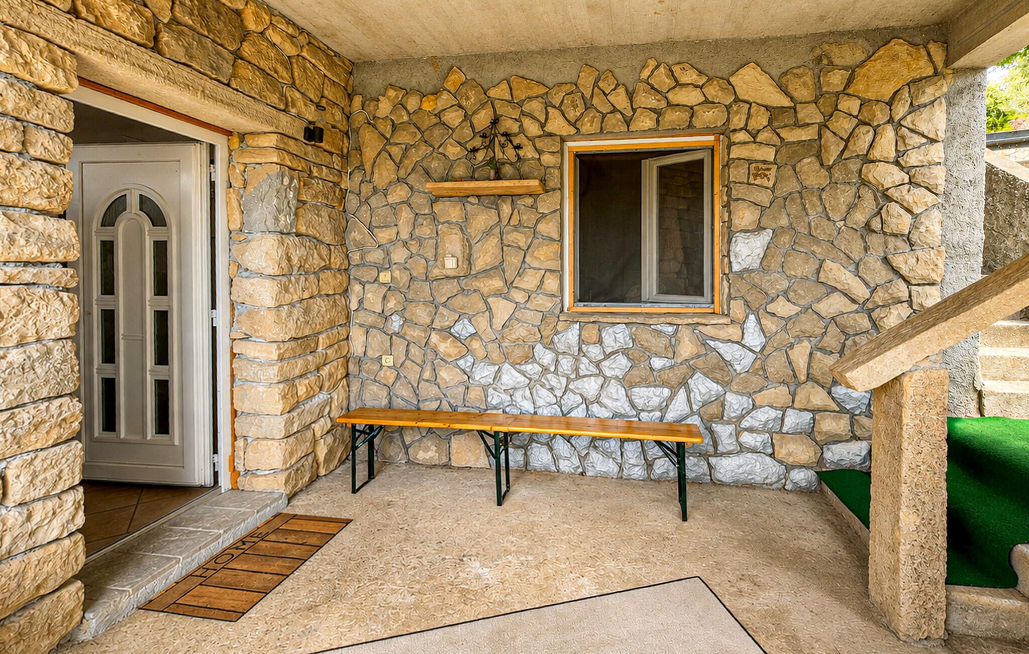 A stone-walled interior with a bench, a door, and a window.