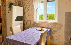 Quarto com mesa posta para dois, janela com vista para vegetação e parede com um mural floral.