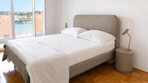 A bed with white linens, a grey headboard, and a bedside lamp. - Gorgeous home in Sibenik (Sibenik)
