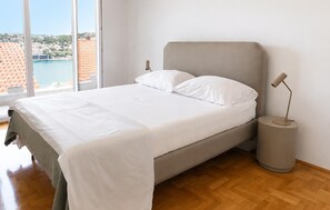 Ein Bett mit weißen Leinen, einem grauen Kopfteil und einer Nachttischlampe.