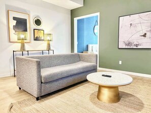 Ein modernes Wohnzimmer mit grauem Sofa, rundem Couchtisch und Bildern an den Wänden.