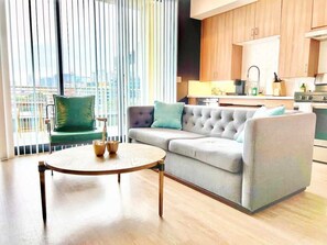 Ein modernes Wohnzimmer mit einer Couch, einem runden Couchtisch und Blick auf die Stadt durch große Fenster.