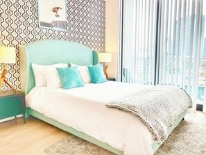 Ein modernes Schlafzimmer mit einem Bett, zwei Nachttischen, einer Wand mit Muster und Blick durch große Fenster.