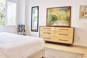 Ein Schlafzimmer mit einem Bett, einer Kommode, einem Spiegel und zwei Bildern an der Wand.