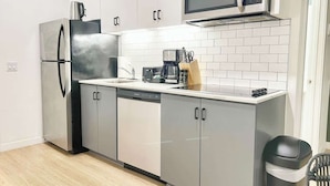 A modern kitchen with a stainless steel refrigerator, a microwave, a dishwasher, and a coffee maker on the counter. - King Bed Gaslamp, Beaches & Padres Nearby (San Diego)