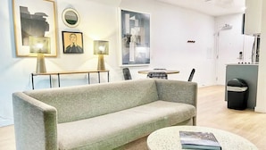 A modern living room with a sofa, a round coffee table, and artwork on the walls. - King Bed Gaslamp, Beaches & Padres Nearby (San Diego)