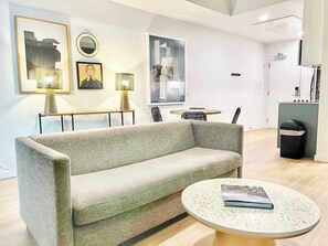 En moderne stue med en sofa, et rundt sofabord og kunst på væggene.