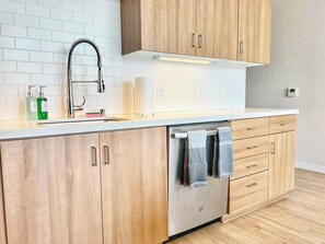 Eine moderne Küche mit Holzausstattung, einem Edelstahl-Geschirrspüler und einer weißen Arbeitsplatte.