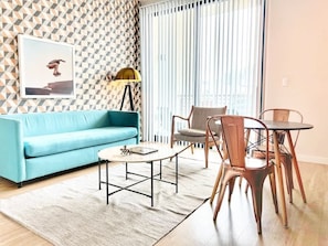Ein Wohnzimmer mit einem blauen Sofa, einem Couchtisch und einem Essbereich mit Stühlen und einem Tisch.