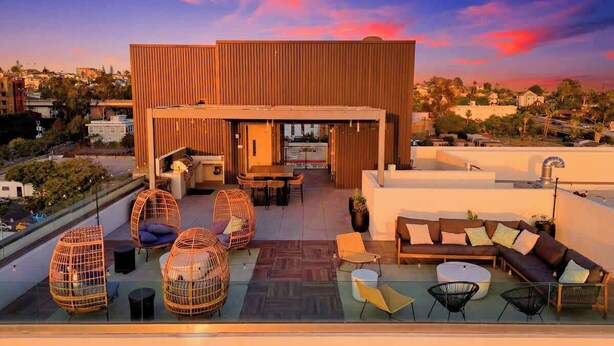 A rooftop terrace with seating arrangements, a bar area, and a view of the cityscape.