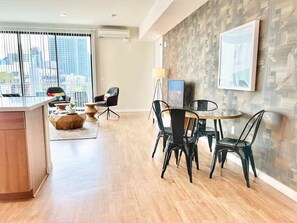Ein modernes Wohnzimmer mit Essbereich, großen Fenstern und Blick auf die Stadt.