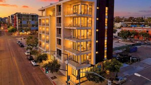 A multi-story hotel with balconies, a parking lot, and a sunset sky.