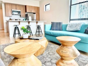 Ein modernes Wohnzimmer mit einer Couch, Couchtischen und einer Küche im Hintergrund.