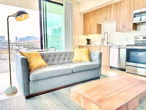 Eine moderne Küche mit grauem Sofa, Holzschränken und Edelstahlgeräten.