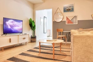 A modern living room with a flat-screen TV, a sofa, a coffee table, and a potted plant. - Stylish San Diego Apt | Gaslamp at Your Door (San Diego)